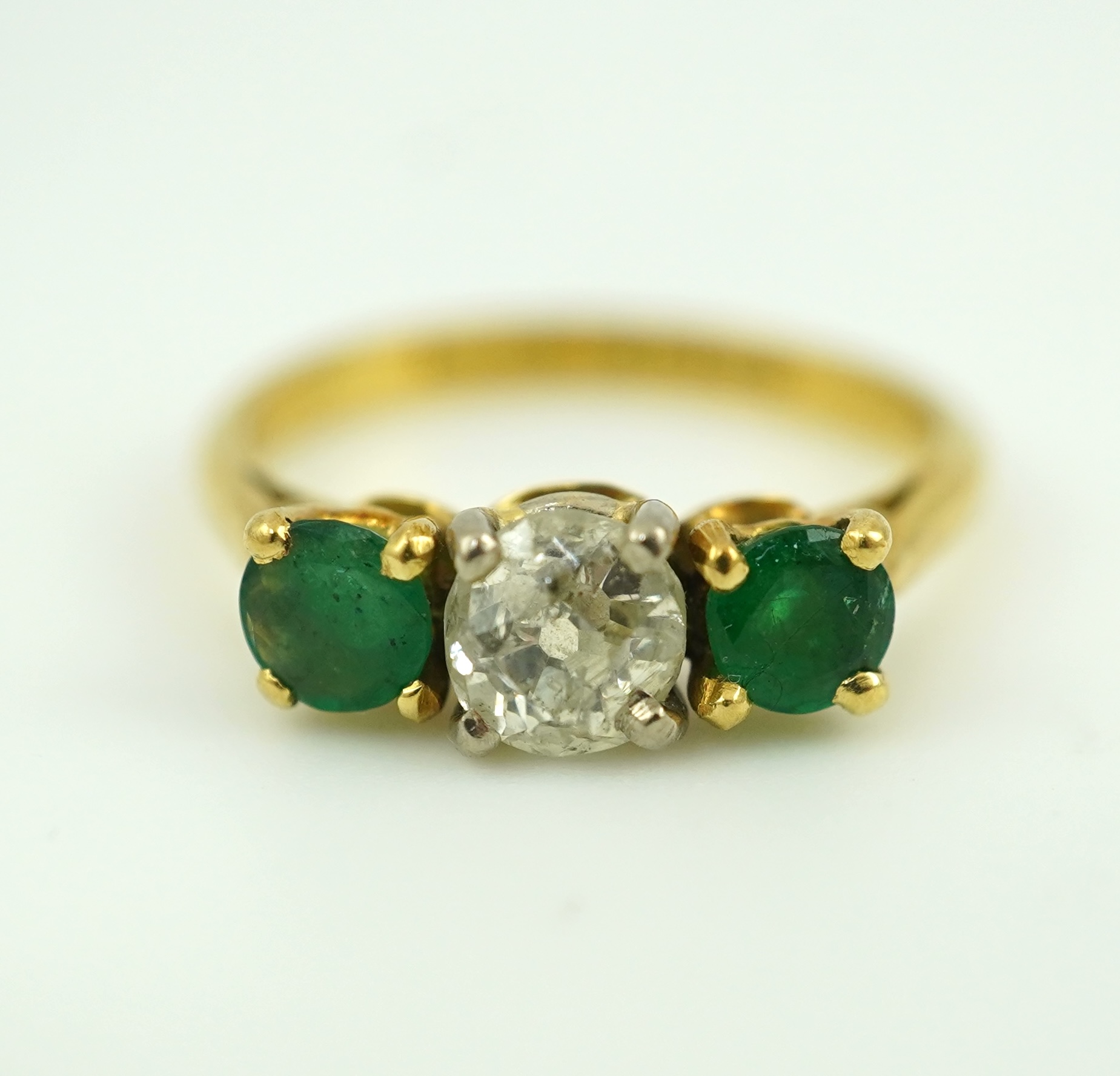 An emerald and diamond three-stone ring